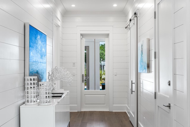 entrance foyer with dark wood-type flooring, wooden walls, and a barn door