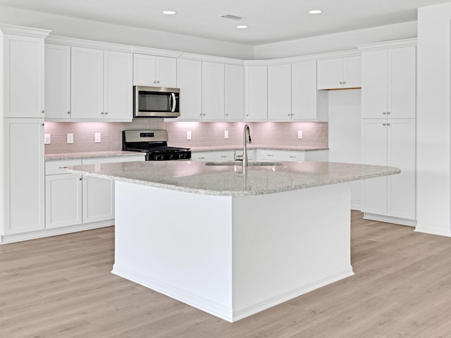 kitchen with appliances with stainless steel finishes, white cabinetry, light wood-type flooring, and sink