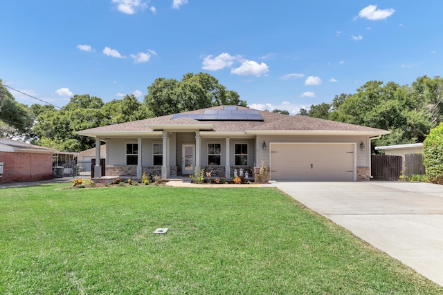 view of front facade featuring a front yard, a garage, a porch, and solar panels