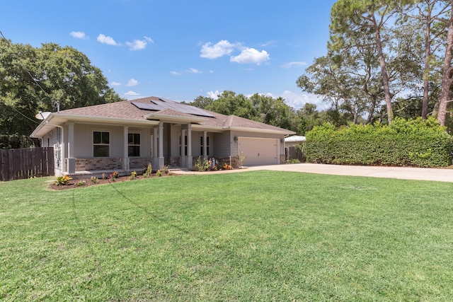 ranch-style home featuring driveway, an attached garage, fence, roof mounted solar panels, and a front lawn