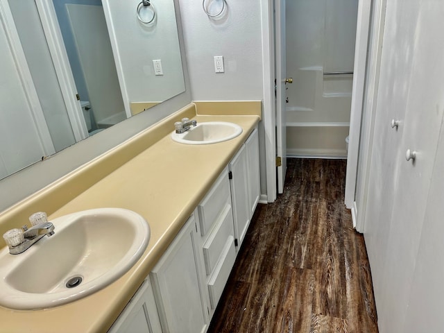 full bathroom with shower / washtub combination, dual vanity, toilet, and hardwood / wood-style floors