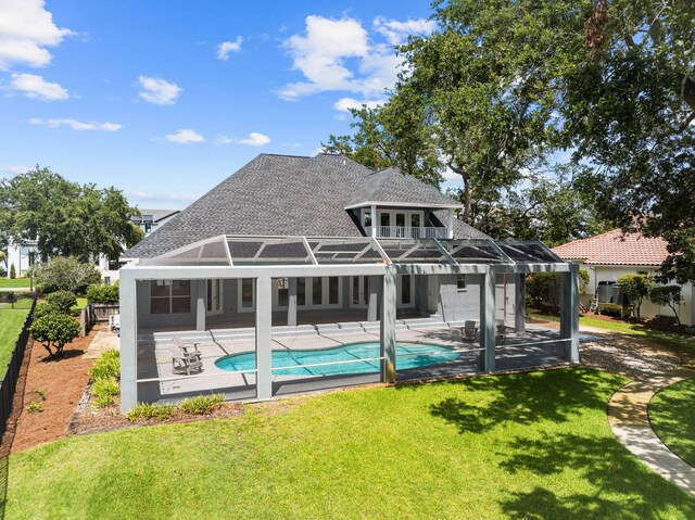 rear view of property featuring a lawn, a patio area, and a lanai