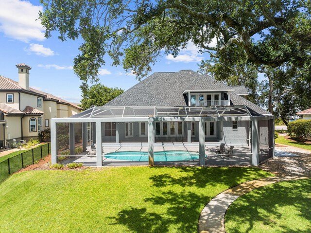 back of property with a lawn, a lanai, a patio area, and a fenced in pool