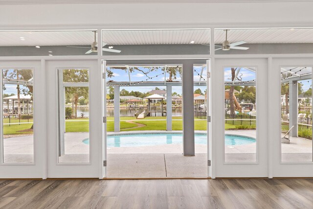 doorway with a water view, ceiling fan, and hardwood / wood-style flooring