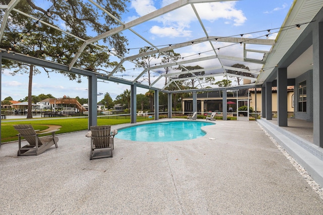 view of pool with a lawn, glass enclosure, and a patio area