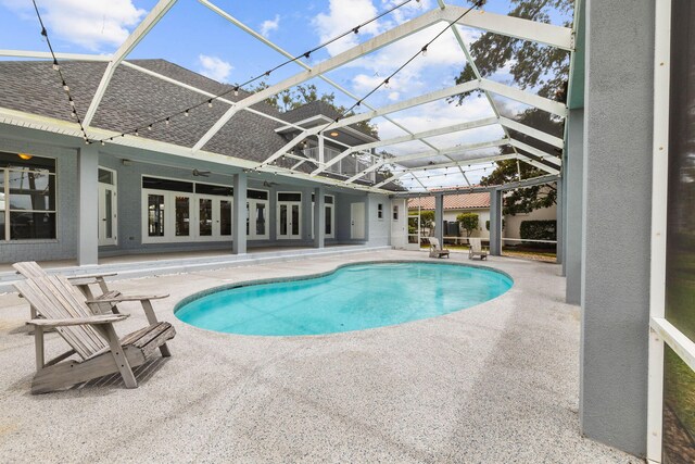 view of pool with a patio, glass enclosure, and ceiling fan