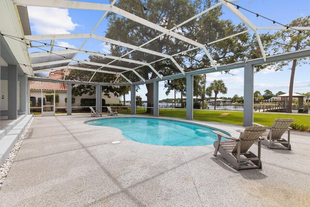 view of pool with glass enclosure, a patio area, a water view, and a yard