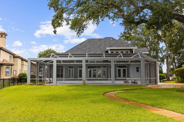 rear view of property featuring a lawn and glass enclosure