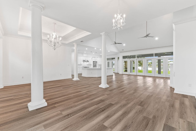 unfurnished living room featuring hardwood / wood-style floors, ceiling fan with notable chandelier, a tray ceiling, and crown molding