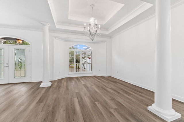 unfurnished dining area with french doors, a raised ceiling, crown molding, hardwood / wood-style flooring, and a notable chandelier