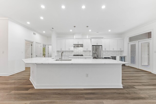 kitchen with white cabinetry, stainless steel fridge, a large island, and sink