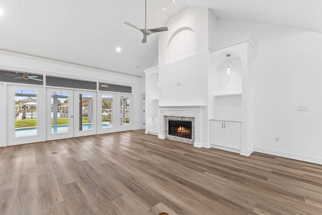 unfurnished living room featuring high vaulted ceiling, french doors, hardwood / wood-style flooring, built in shelves, and a fireplace