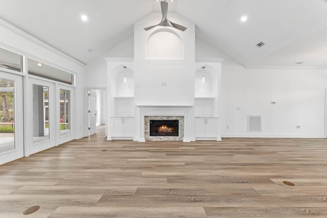 unfurnished living room with light hardwood / wood-style floors, built in features, a fireplace, and high vaulted ceiling