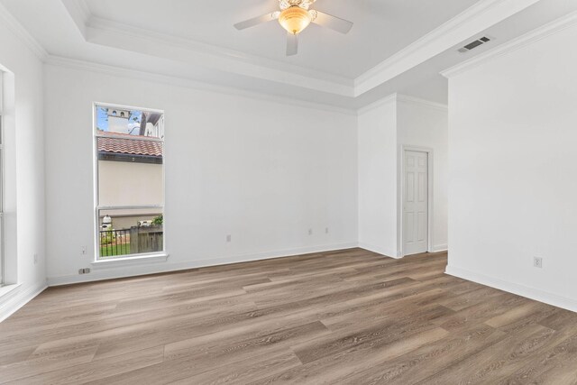 spare room featuring a tray ceiling, hardwood / wood-style flooring, crown molding, and ceiling fan