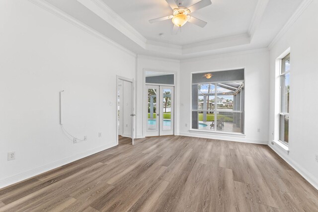 spare room with a raised ceiling, ceiling fan, crown molding, and light hardwood / wood-style floors