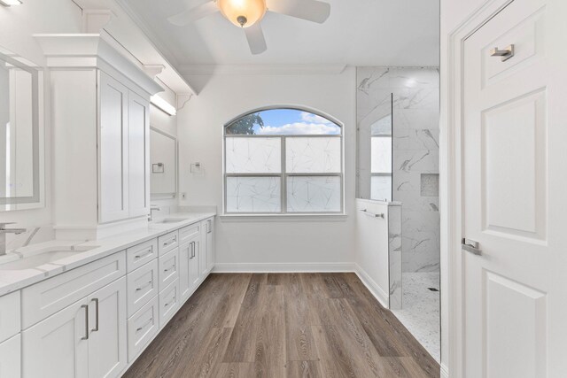 bathroom with hardwood / wood-style floors, vanity, crown molding, ceiling fan, and a tile shower