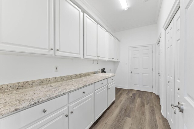 laundry room with hardwood / wood-style flooring, sink, and crown molding