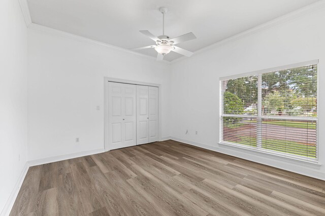 unfurnished bedroom with a closet, ceiling fan, crown molding, and light hardwood / wood-style floors