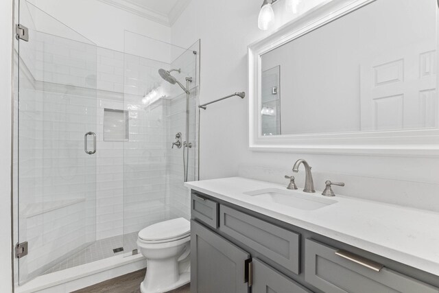 bathroom with vanity, toilet, ornamental molding, an enclosed shower, and wood-type flooring