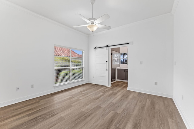 1780 Driftwood Point Rd, Santa Rosa Beach, FL 32459 - spare room featuring a barn door, light wood-style flooring, a ceiling fan, and ornamental molding