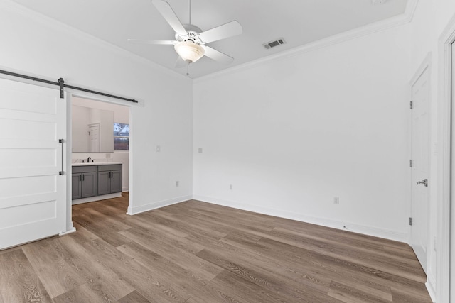 1780 Driftwood Point Rd, Santa Rosa Beach, FL 32459 - unfurnished bedroom featuring visible vents, ornamental molding, light wood-style flooring, a barn door, and baseboards