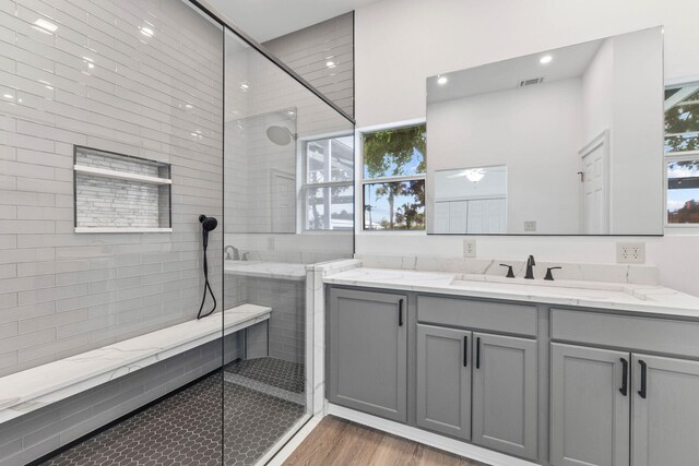 bathroom featuring wood-type flooring, vanity, a wealth of natural light, and a shower with shower door