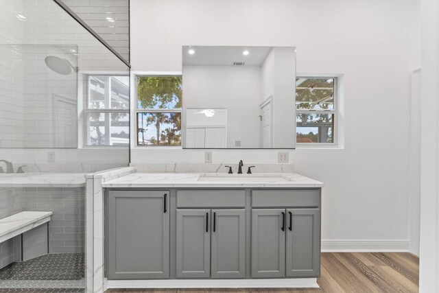 bathroom featuring hardwood / wood-style floors, vanity, and tiled shower