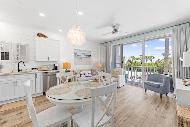 dining space featuring sink, light hardwood / wood-style flooring, and ceiling fan with notable chandelier