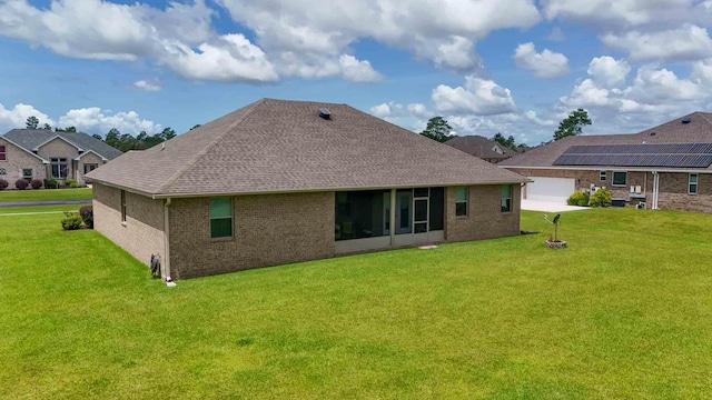 rear view of property featuring a yard, a sunroom, and a garage