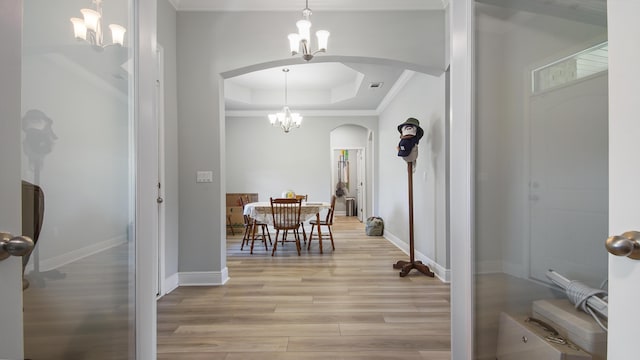 dining room with crown molding, light hardwood / wood-style flooring, a chandelier, and a tray ceiling