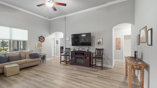 living room featuring a high ceiling, crown molding, ceiling fan, and light wood-type flooring