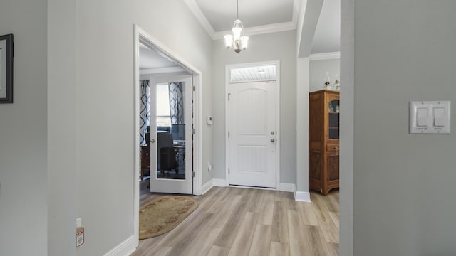 foyer entrance with crown molding, a chandelier, and light wood-type flooring