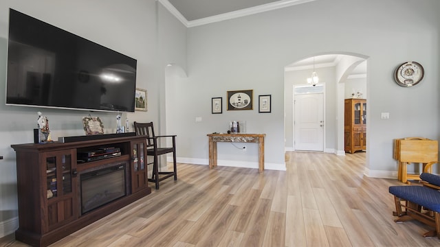 living room with a high ceiling, ornamental molding, and light hardwood / wood-style flooring