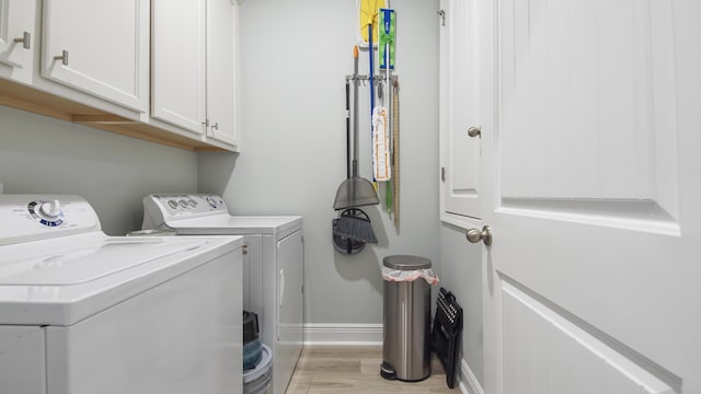 laundry area featuring cabinets, washing machine and dryer, and light hardwood / wood-style floors