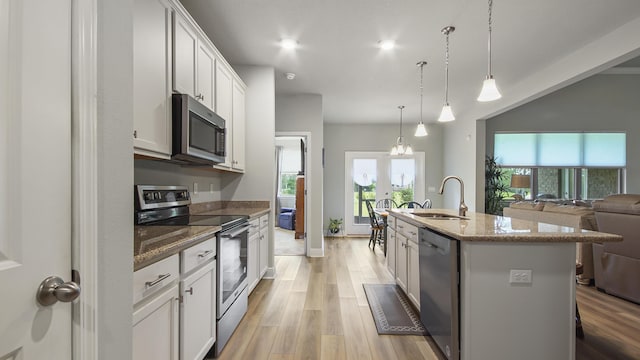 kitchen featuring sink, appliances with stainless steel finishes, an island with sink, pendant lighting, and white cabinets