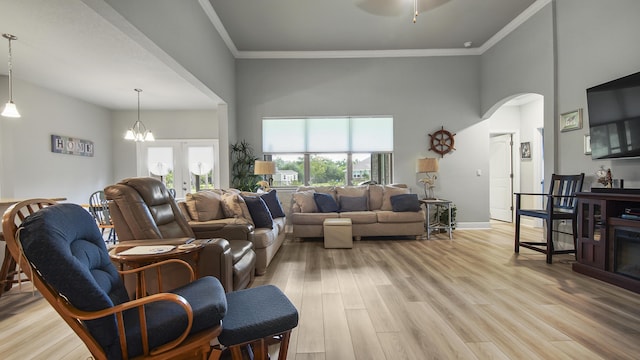 living room with crown molding, a towering ceiling, light hardwood / wood-style flooring, and french doors