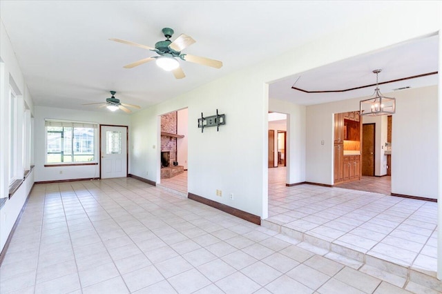 empty room featuring ceiling fan with notable chandelier, light tile patterned flooring, and a brick fireplace