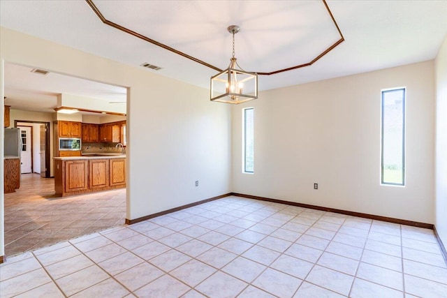 tiled empty room featuring a chandelier