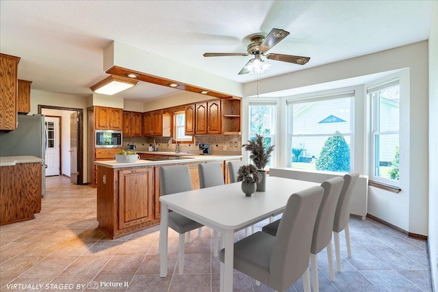 kitchen with backsplash, kitchen peninsula, ceiling fan, and appliances with stainless steel finishes