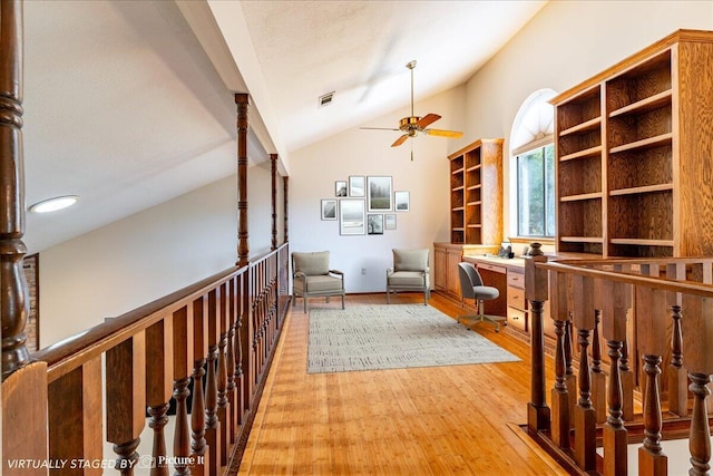 living area featuring ceiling fan, light hardwood / wood-style flooring, built in desk, and vaulted ceiling