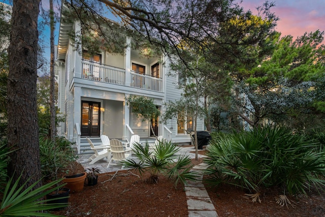 back house at dusk with a patio area and a balcony