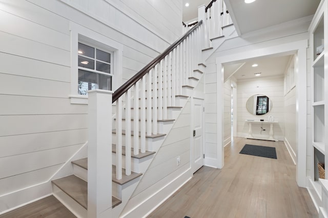 stairs featuring wood-type flooring and wood walls