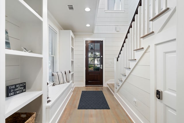 mudroom featuring crown molding, wood-type flooring, and wood walls