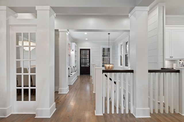 corridor with hardwood / wood-style floors, ornamental molding, decorative columns, and a healthy amount of sunlight