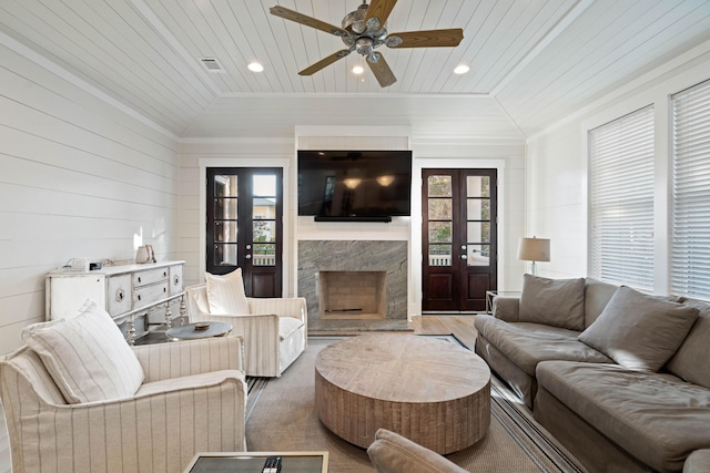 living room featuring ornamental molding, lofted ceiling, a premium fireplace, and wooden ceiling