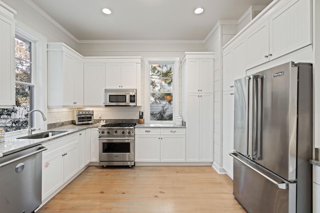 kitchen with sink, white cabinets, high end appliances, light hardwood / wood-style floors, and light stone countertops