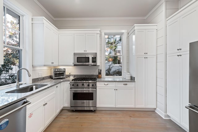 kitchen with appliances with stainless steel finishes, light stone countertops, sink, and white cabinets