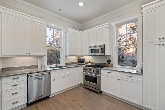 kitchen featuring appliances with stainless steel finishes, sink, light hardwood / wood-style flooring, and white cabinets