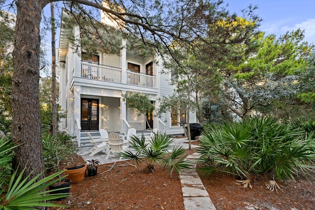 view of front of house featuring a balcony and french doors