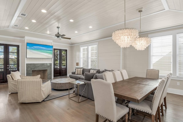 dining area with vaulted ceiling, hardwood / wood-style flooring, a high end fireplace, wood ceiling, and french doors